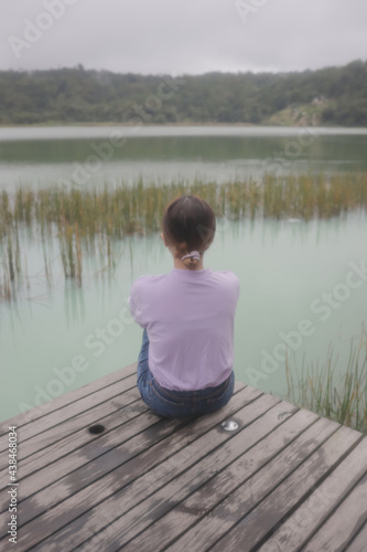 a woman sitting by the lake