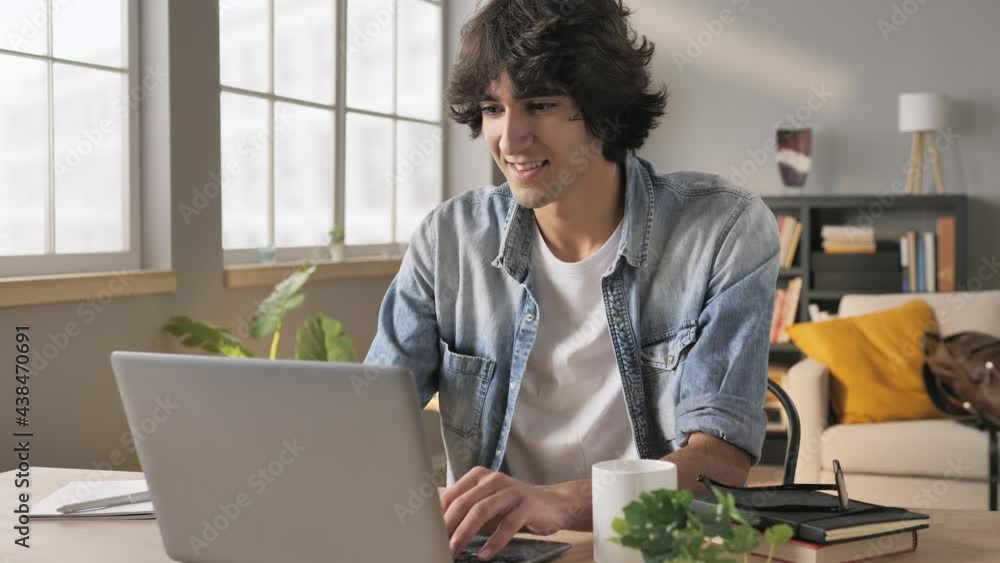 Middle eastern man using laptop computer at his desk typing and looking satisfied,young arab male working at the notebook looks happy,pleased,startup business concept