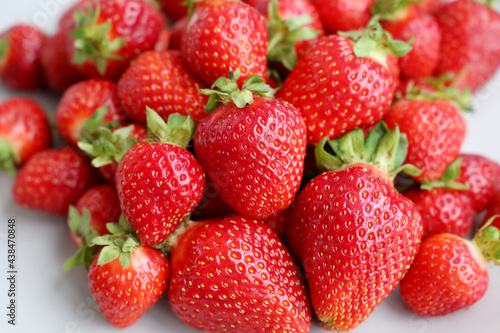 Ripe red strawberries with leaves on a white plate. Fresh strawberry for background