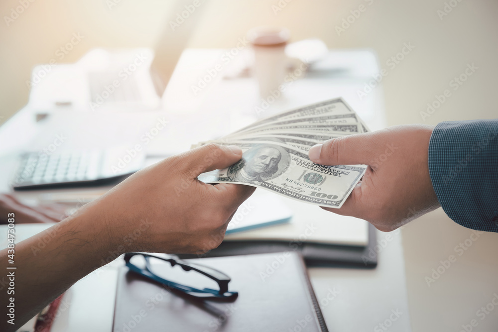 Man offering batch of hundred dollar bills. Hand of a businessman giving money to his partner. Hand receiving money from businessman. Venality, bribe, corruption concept. Man offering batch of hundred dollar bills. Hand of a businessman giving money to his partner. Hand receiving money from businessman. Venality, bribe, corruption concept.