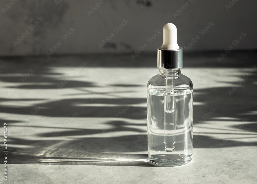 Herbal oil in glass bottle with dropper pipette on grey background with shadows, free space for text, alternative medicine or skin care concept Herbal oil in glass bottle with dropper pipette on grey background with shadows, free space for text, alternative medicine or skin care concept