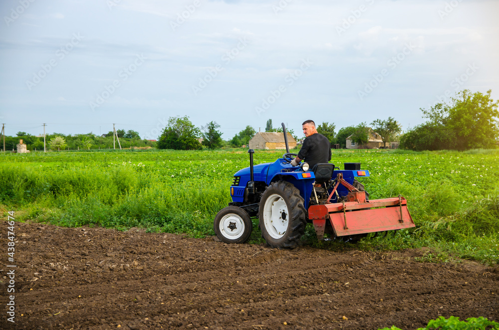 A farmer with a cultivation unit on a tractor rides to cultivate a field. Milling soil, crushing before cutting rows. Agribusiness and agroindustry. Loosening surface, land cultivation. Plowing field. A farmer with a cultivation unit on a tractor rides to cultivate a field. Milling soil, crushing before cutting rows. Agribusiness and agroindustry. Loosening surface, land cultivation. Plowing field.