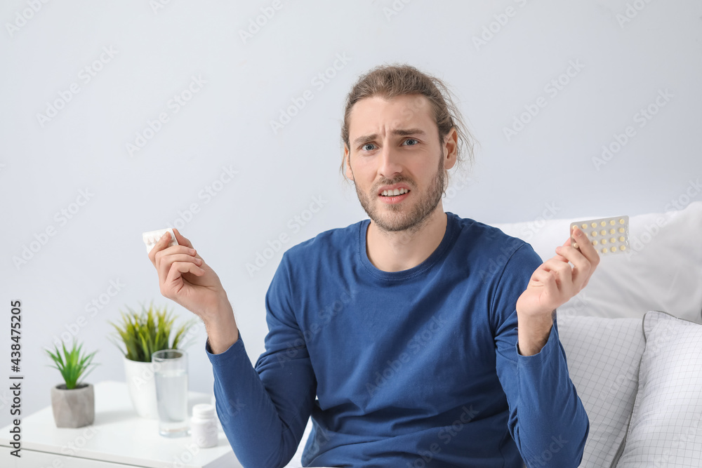 Displeased young man with pills at home Displeased young man with pills at home