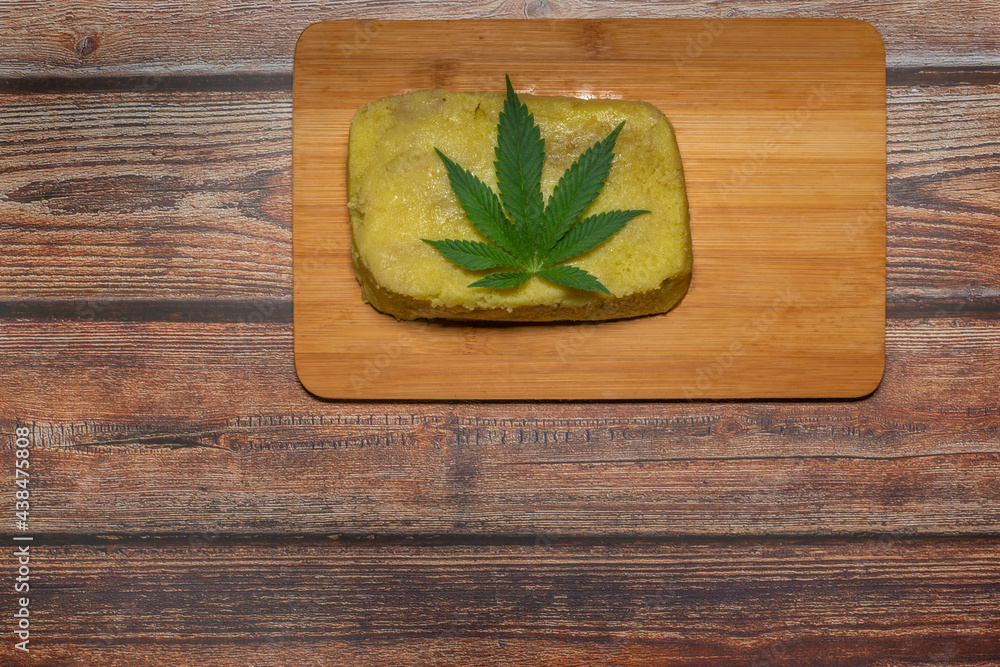 Marijuana butter on wooden table with green leafs