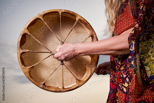 detailed shot of the back of a leather ceremonial drum being held by someone in brightly dressed ceremonial robes.