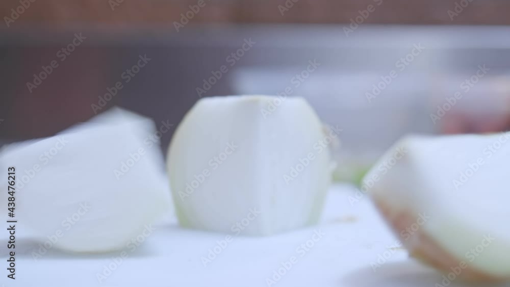 Close up view of a hands cut onion in black gloves. Cut onions on a white chopping board. prepares food Close up view of a hands cut onion in black gloves. Cut onions on a white chopping board. prepares food