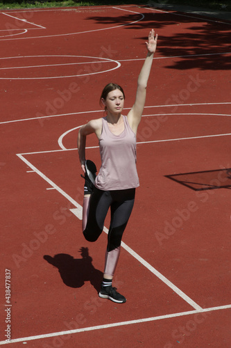 Beautiful female fitness model doing stretch exercises after workout outside on a sport field © triocean
