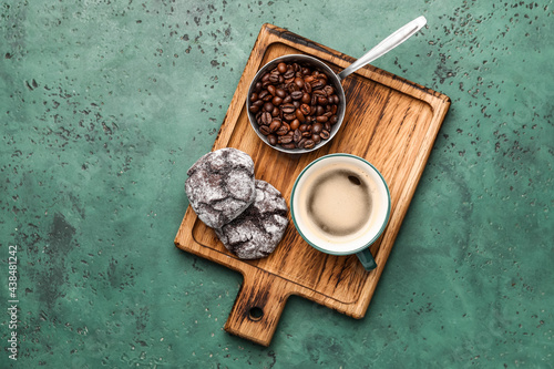 Cup of freshly brewed coffee and cookies on color background
