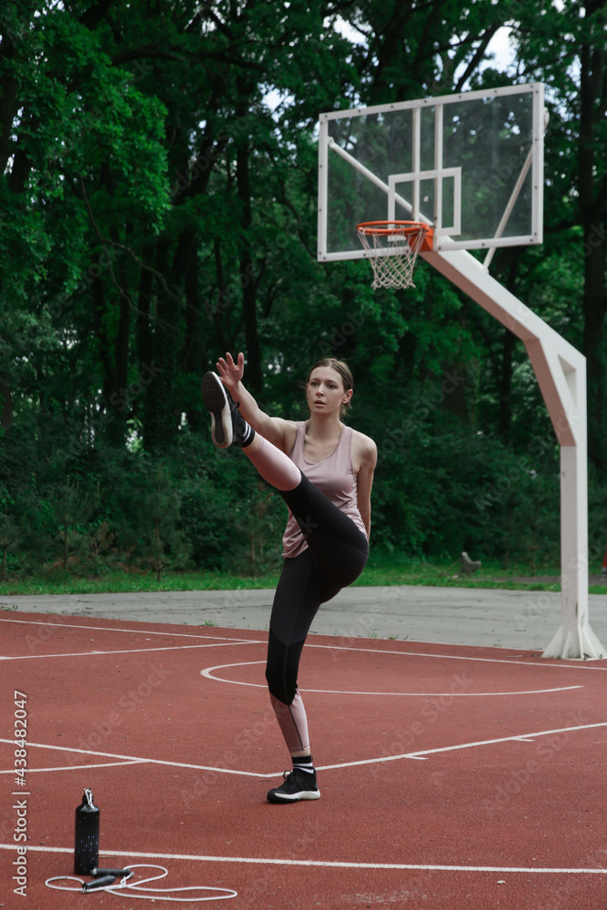 Fit young woman doing a dynamic exercise on a sport field. Cardio training outdoors.
