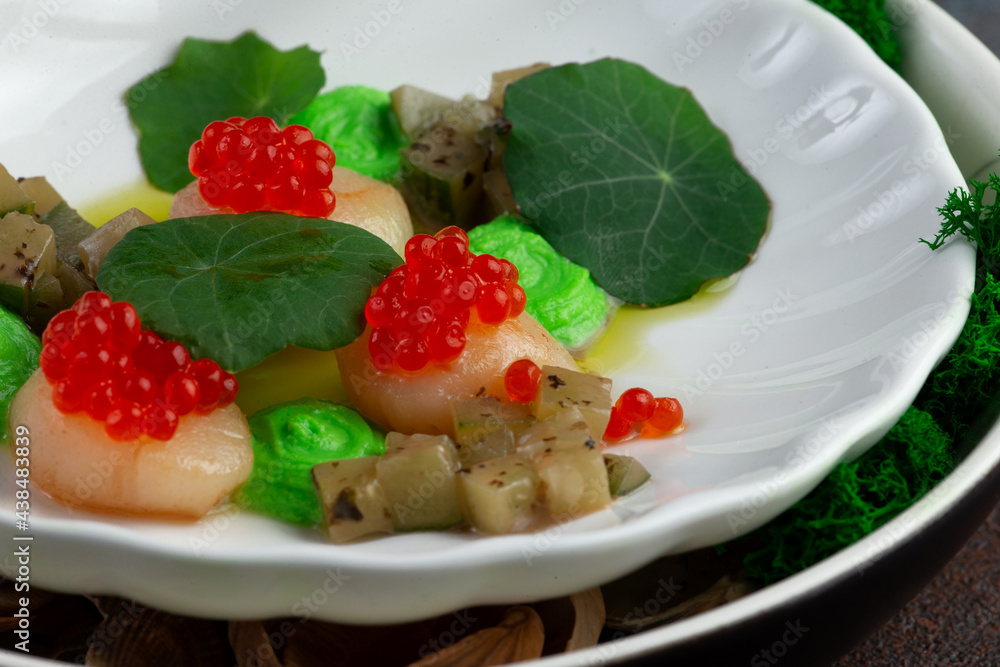 Scallops with caviar, microgreens and green sauce on a white plate. Scallops with caviar, microgreens and green sauce on a white plate.