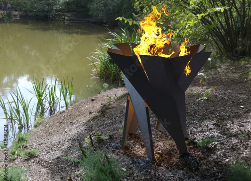 Grill With Big Flame. BBQ in the garden on clear summer day near the water. Modern barbecue grill in summer garden, outside, nobody. BASKET garden fireplace.