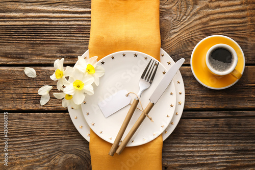 Beautiful table setting with narcissus flowers on wooden background