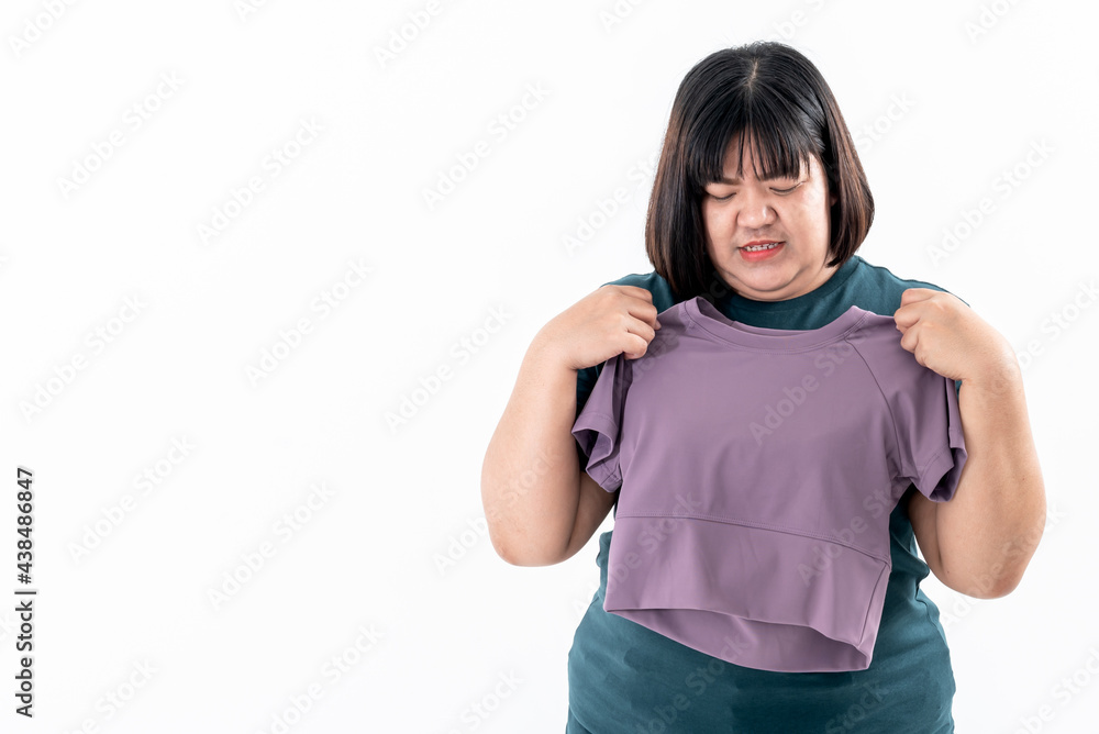 Portrait images of Asian fat woman looking and holding a shirt which is smaller than her body, to inspire weight loss, on white background, to fat woman and weight loss concept. Portrait images of Asian fat woman looking and holding a shirt which is smaller than her body, to inspire weight loss, on white background, to fat woman and weight loss concept.