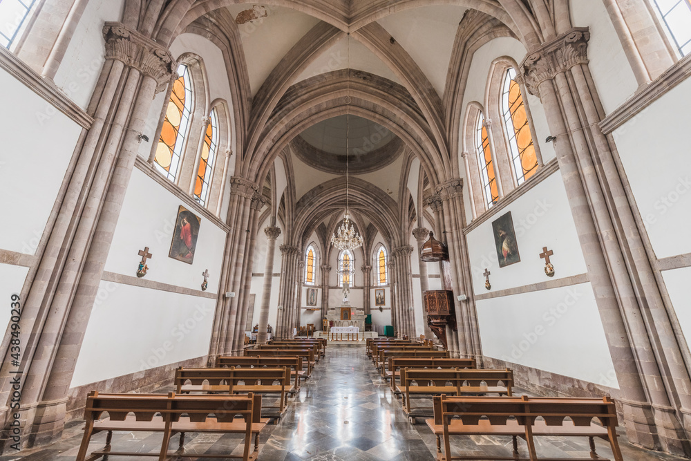 Obraz premium Interiors and details of the Cathedral of Angangueo, Michoacán, Mexico, you can see symmetry in its columns of a Gothic style, the wooden details such as its benches and the pulpit.