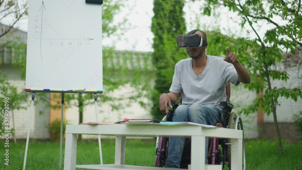 Talented creative African American disabled man in wheelchair using VR headset designing project on spring backyard. Wide shot of concentrated confident skilled designer working in virtual reality Talented creative African American disabled man in wheelchair using VR headset designing project on spring backyard. Wide shot of concentrated confident skilled designer working in virtual reality