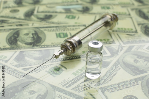 Glass syringe and vial with vaccine against the background of american dollars