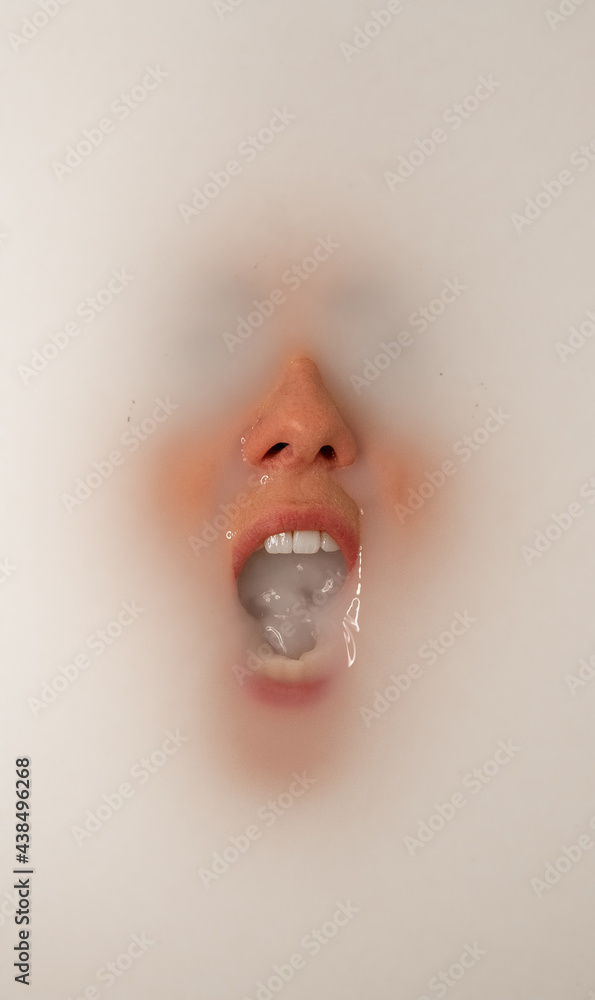 Woman underwater with her mouth open and filled with milk. Milk surrounds her face and covers her eyes. She appears to be screaming under the water. Woman underwater with her mouth open and filled with milk. Milk surrounds her face and covers her eyes. She appears to be screaming under the water.