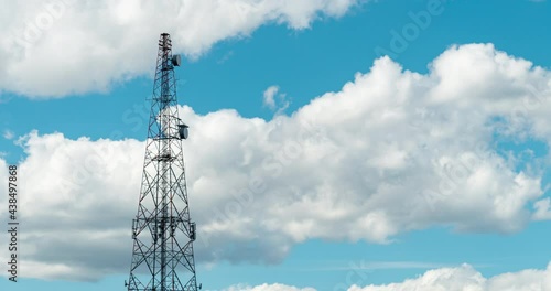 Mobile phone communication radio antenna, 3G, 4G, 5G, 6G. Time Lapse of antenna over fast moving cloudy blue sky at summer. Cellular GSM tower with transmitter. Telecommunication base station network. photo