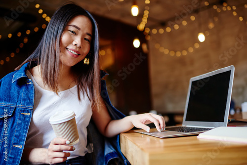 Smiling Asian woman typing on laptop