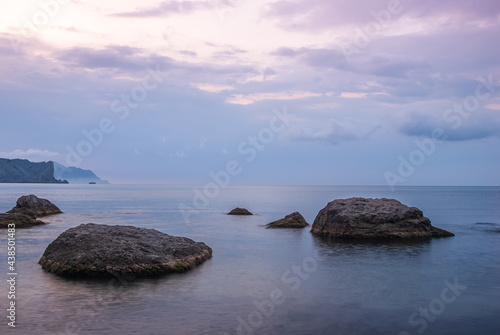 Morning seascape. Sea water at long exposure, stones and rocks. Beautiful sky with clouds.
