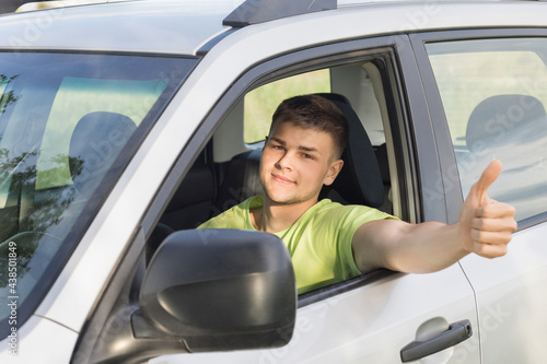 A man driving a car shows hand good.