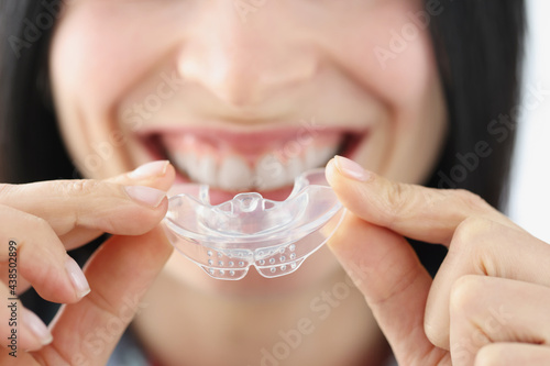 Smiling woman holding plastic mouth guard for teeth whitening