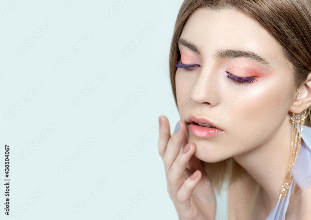 Beautiful young woman with clean perfect skin and blue-pink makeup and feather earings. Portrait of beauty model with natural make up and long eyelashes. Beautiful young woman with clean perfect skin and blue-pink makeup and feather earings. Portrait of beauty model with natural make up and long eyelashes.