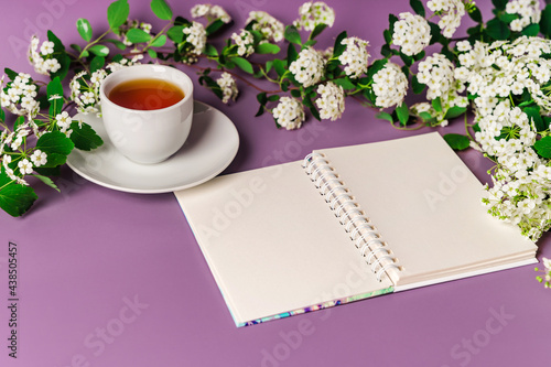 Cozy spring purple background with a mug of tea. Floral composition with space for text