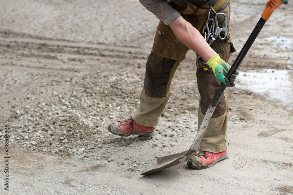 Work with a shovel at a construction site. A worker throws cement and gravel with a shovel. Work with a shovel at a construction site. A worker throws cement and gravel with a shovel.