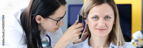 Doctor examines patient's ear with an otoscope