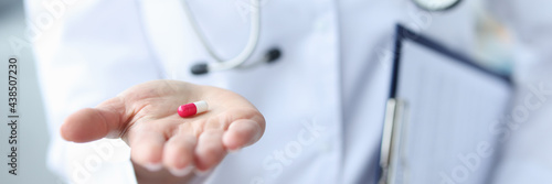 Red-white pill is on the doctor's hand