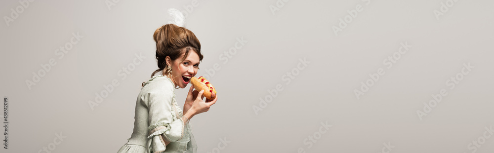 hungry, retro style woman looking at camera while eating hot dog isolated on grey, banner hungry, retro style woman looking at camera while eating hot dog isolated on grey, banner