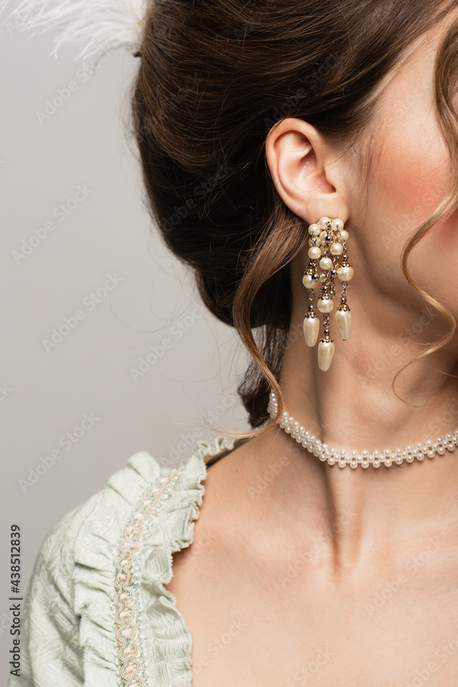 cropped view of woman in pearl necklace and earring isolated on grey