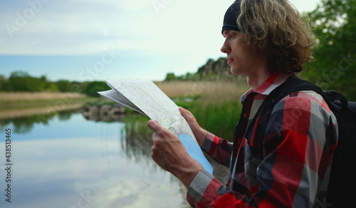Male tourist with map by the lake.