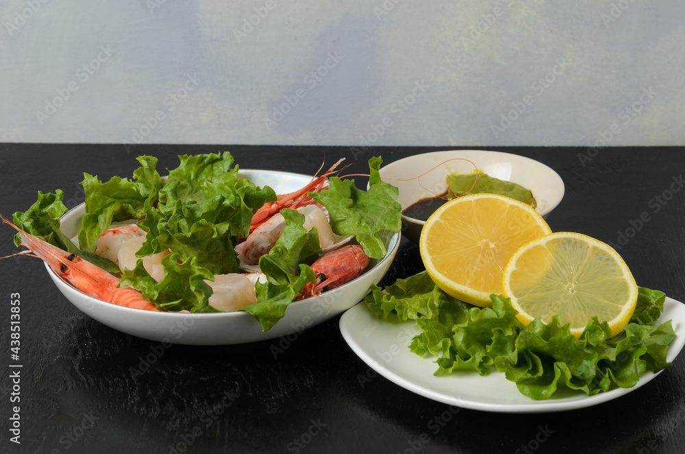 Natural raw scallop with boiled shrimp in the sink in a ceramic bowl with lettuce leaves and sauce on a dark background. Natural raw scallop with boiled shrimp in the sink in a ceramic bowl with lettuce leaves and sauce on a dark background.