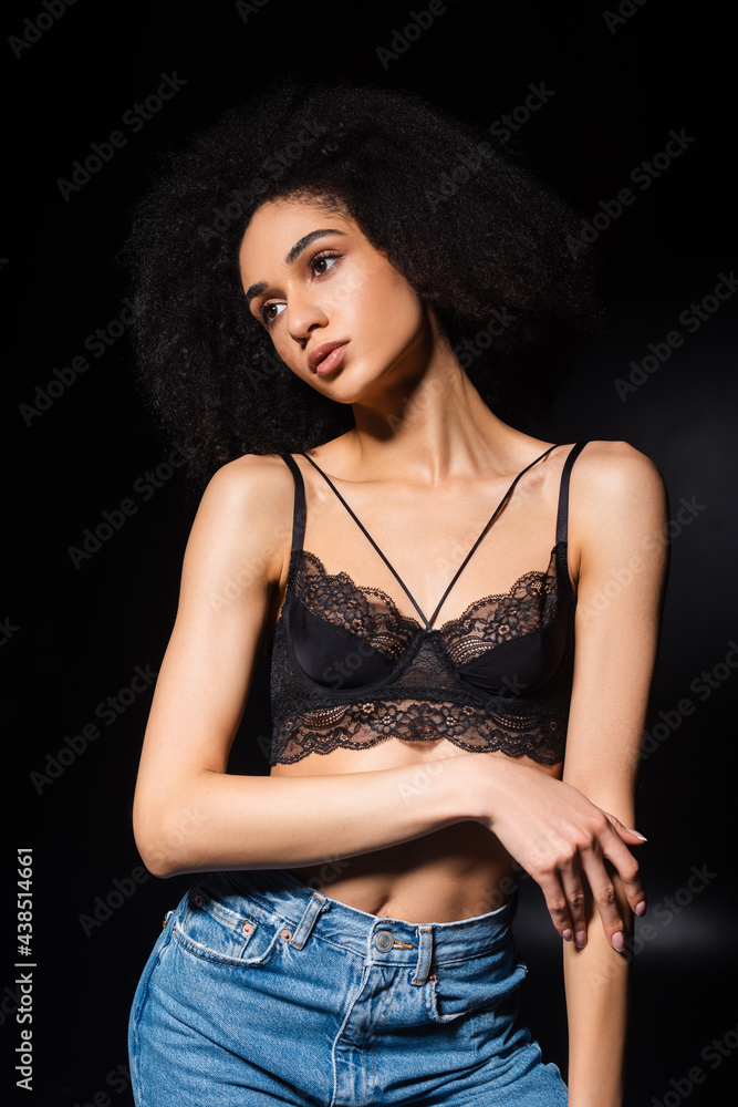 Pretty african american woman in bra touching arm on black background Pretty african american woman in bra touching arm on black background