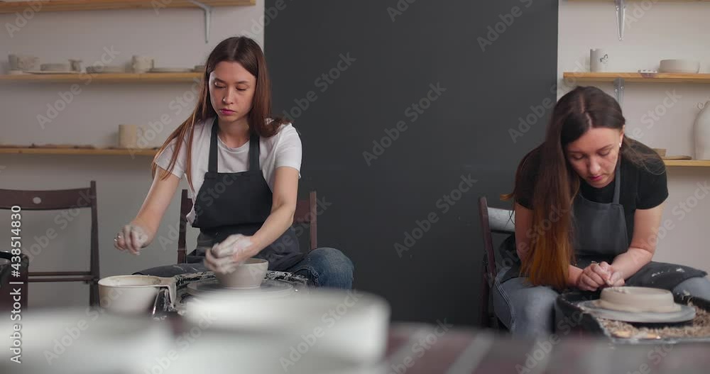 Pottery studio concept. Two young woman using pottery wheel, handmade ceramics, creative. Slow motion Pottery studio concept. Two young woman using pottery wheel, handmade ceramics, creative. Slow motion