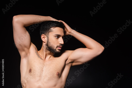 Muscular man posing and looking away isolated on black