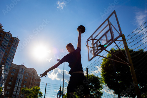 Young red-haired guy throws a ball into a basketball hoop