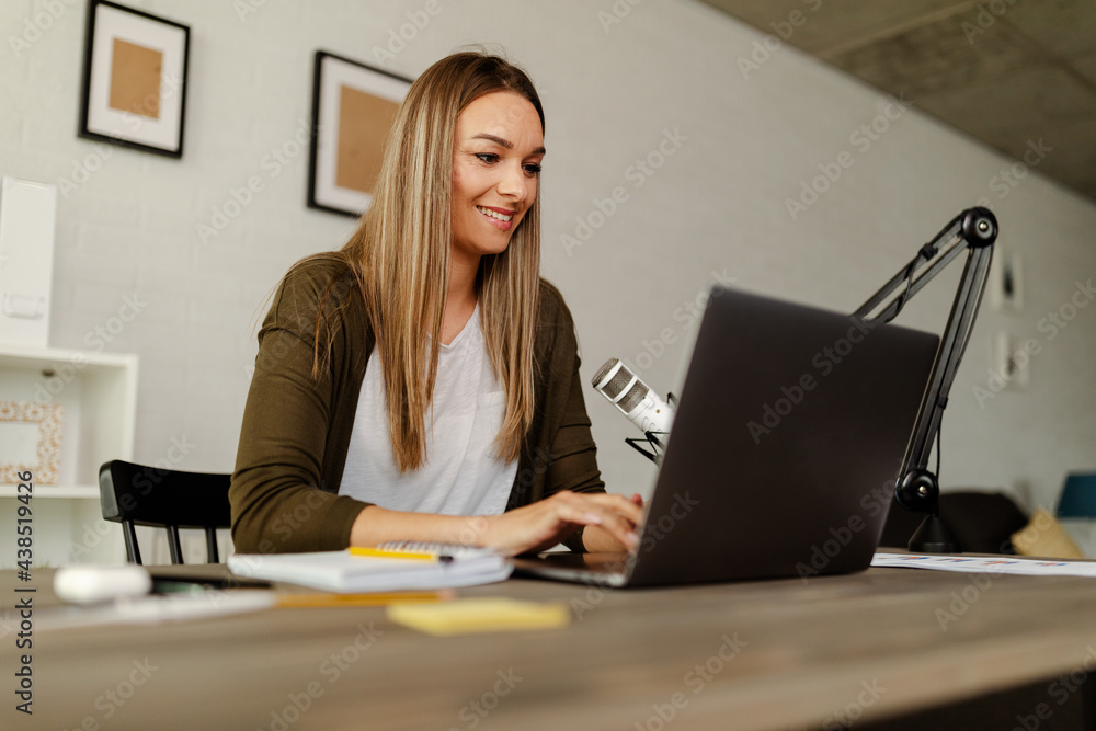 Woman smiling while working on laptop at home. Woman smiling while working on laptop at home.