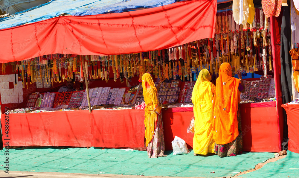 Pushkar, India - November 10, 2016: Bunch of women in traditional hindu wear saree buying or shopping jewelery items in the commercial street of Pushkar fair in the state of Rajasthan