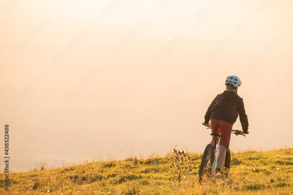 Girl child riding mountain bike into the sunset. Beautiful golden summer light. Girl child riding mountain bike into the sunset. Beautiful golden summer light.