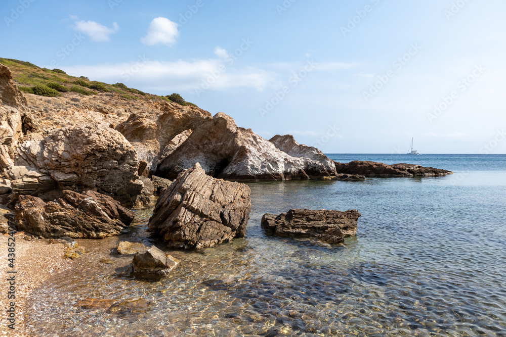 Wild pebble beach on mediterranean sea with rocky cliffs shore and blue clear water. Travel Greece near Athens. Summer nature scenic lagoon