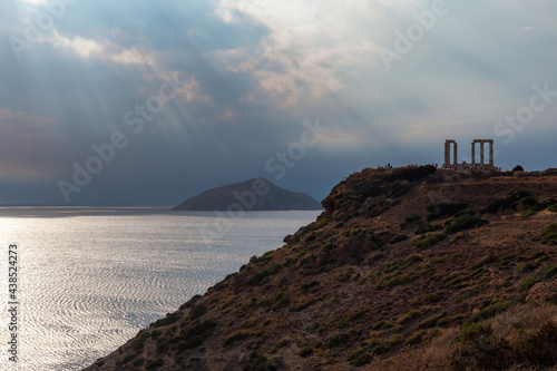 Dramatic cloudscape over the Temple of Poseidon at Cape Sounion, Greece. Ruins of an ancient Greek temple with Doric-style columns on cliff with epic views on mediterranean sea
