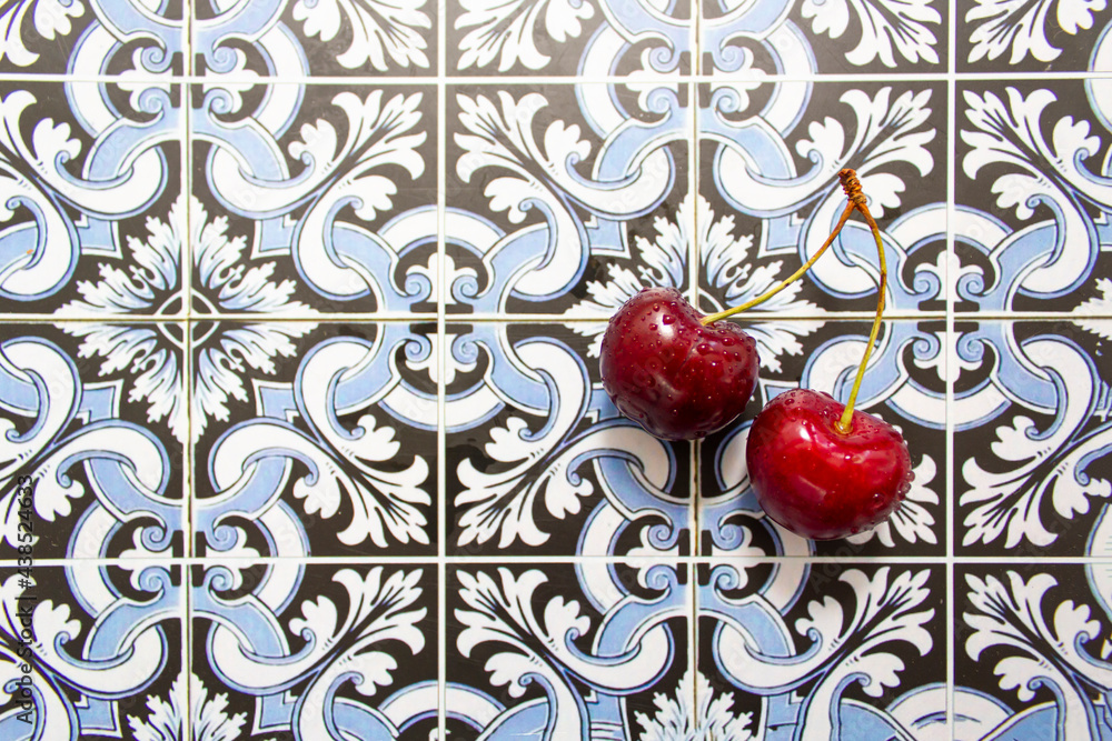 Pair of red fresh cherries on portuguese tiles background