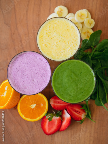 Three fruit smoothies with fruit on the side