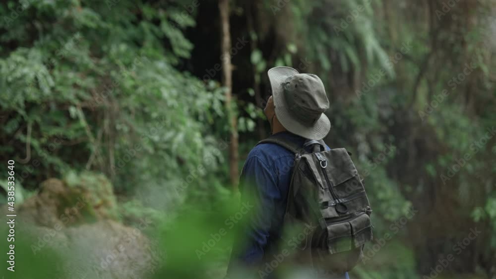 The Backpacker are traveling in the rain forest with beautiful water fall nature. Young Asians go on a journey through the forest. Back view hikers standing at waterfall. The Backpacker are traveling in the rain forest with beautiful water fall nature. Young Asians go on a journey through the forest. Back view hikers standing at waterfall.