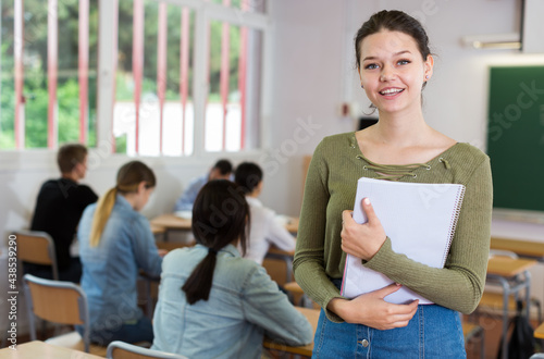 Portrait of girl who is standing satisfied after lecture in the classroom in the school.