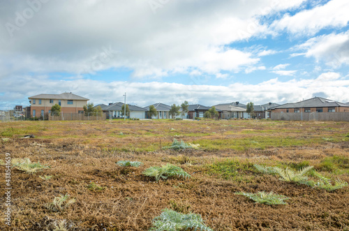 Fenced vacant land near some Australian new residential suburban houses. Concept of real estate development, housing, land for sale and a new suburb, Tarneit, Melbourne, VIC Australia. photo