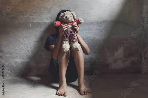 Canvas Print Child covered her face sitting alone on floor with her bear in dark room